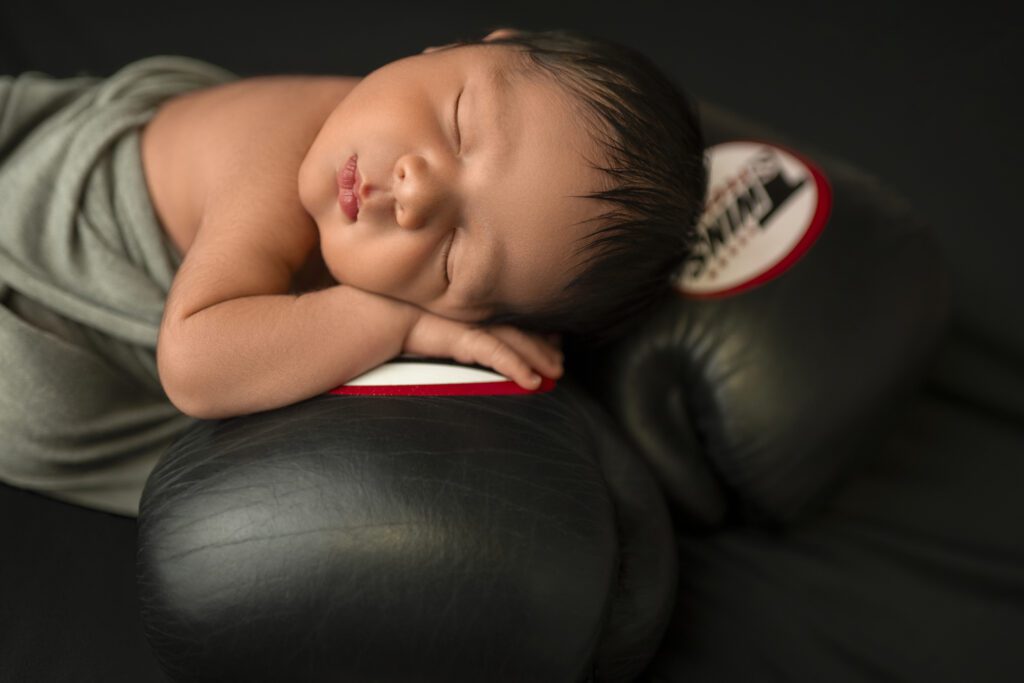 Baby posed on boxing gloves for newborn session 

