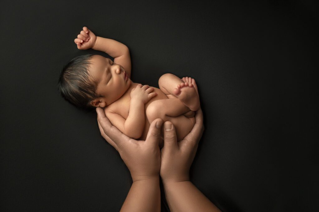 Baby posed in father's hands for newborn session 